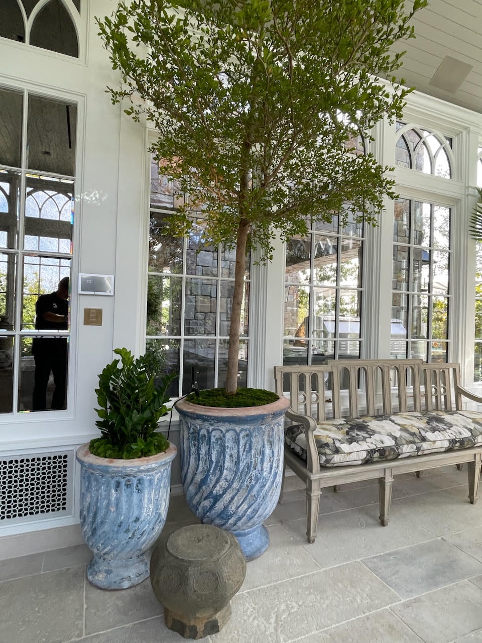 Blue swirl-glazed urns planted with a topiary tree in a sunroom