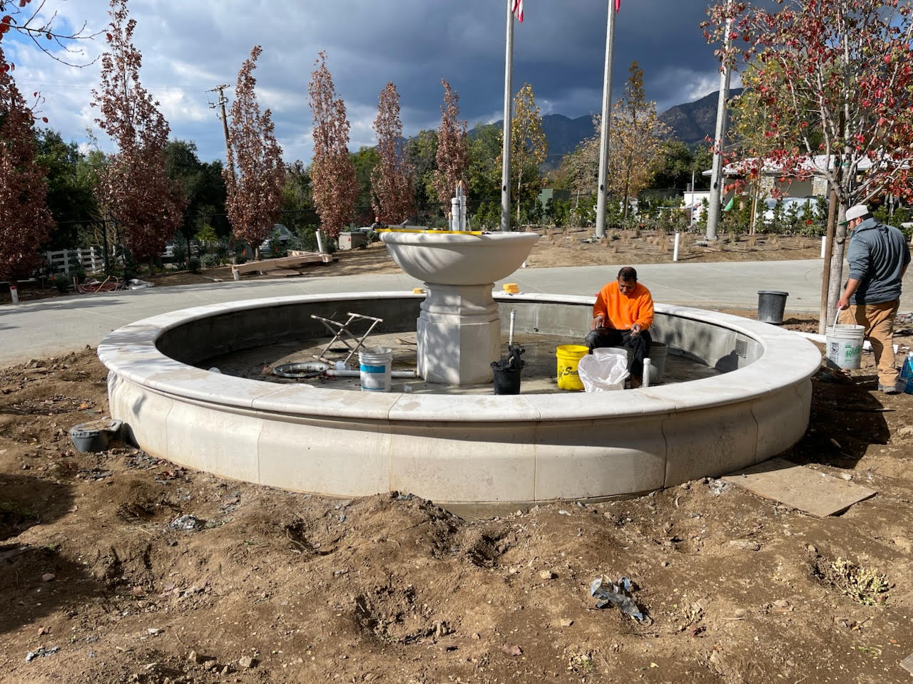 Craftsmen assembling a large tiered fountain basin on site