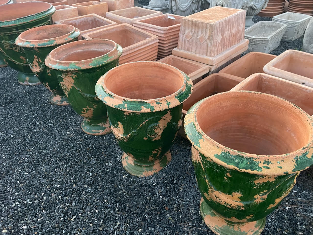 Green-glazed Anduze urns beside rows of terra cotta planters